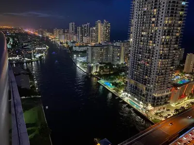 a view of a city at night with a river at Sunny Studio Stay, 2 Full Beds, Coastal Walks Nearby in Hallandale Beach
