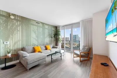 a living room with a couch and a table at Water View Building With Pool - 5-Min Walk To The Beach in Hallandale Beach