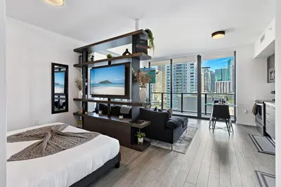 a bedroom with a large bed and a living room at Corner condo w/ Unrivaled views in Miami