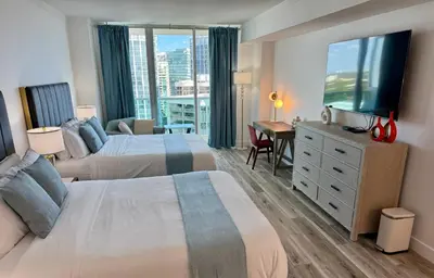 a hotel room with two beds and a flat screen tv at Balcony Ocean View ! WiFi - Pool - Gym - Parking in Miami