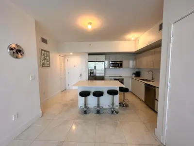 a kitchen with a table and some stools in it at Oceanview Luxury 2BR with Pool & Beach in Hallandale Beach