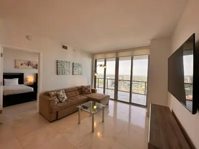 a living room with a couch and a bed at Oceanview Luxury 2BR with Pool & Beach in Hallandale Beach