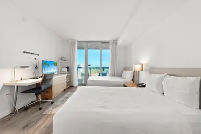 a hotel room with a bed and a desk with a computer at Water View Building With Pool - 5-Min Walk To The Beach - Cozy Studios in Hallandale Beach