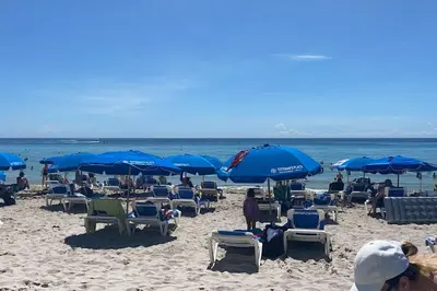 a beach with many chairs and blue umbrellas at Hallandale Beach, Pool, Gym & More in Hallandale Beach