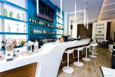 a bar with a white counter and bar stools at Hallandale Beach, Pool, Gym & More in Hallandale Beach