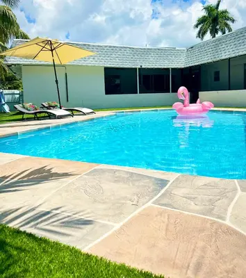 a swimming pool with a pink flamingo in the water at Game & Chill Manor - Arcade - Pool - Pool table in Fort Lauderdale