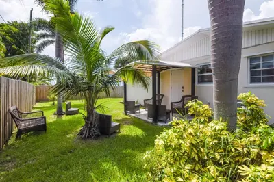 a yard with benches and palm trees in front of a house at Patio and Yard Family-Friendly Miami Oasis! in Miami Gardens