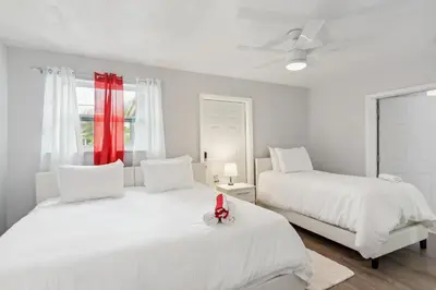 a white bedroom with two beds and a window at Patio and Yard Family-Friendly Miami Oasis! in Miami Gardens