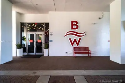 a red bench in front of a building with a bwk sign at Modern Studio Escape at BeachWalk, Perfect for Small Groups -B in Hallandale Beach