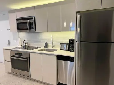 a kitchen with a stainless steel refrigerator and a sink at Oceanfront Elegance, Full Kitchen & Miami Beach Charm -1A in Hallandale Beach