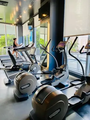 a gym with treadmills and a woman sitting on a treadmill at Cozy Beach Apartment with Full Kitchen -A in Hallandale Beach