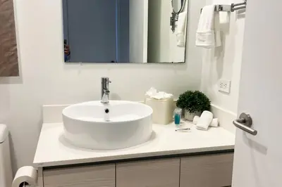 a white bathroom with a sink and a mirror at Walk to the Beach, Sleep in Comfort, Studio for 4 in Hallandale Beach