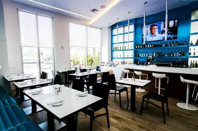 a restaurant with tables and chairs and a bar at Walk to the Beach, Sleep in Comfort, Studio for 4 in Hallandale Beach