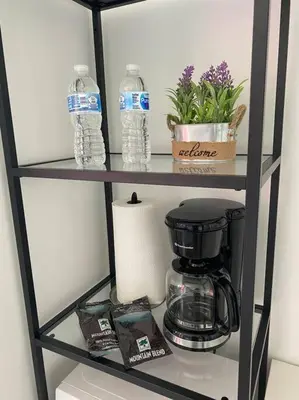 a shelf with a coffee maker and water bottles at Walk to the Beach, Sleep in Comfort, Studio for 4 in Hallandale Beach