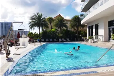 a group of people swimming in a swimming pool at Cozy BeachWalk Nest, 2 Full Beds, Steps to Ocean in Hallandale Beach