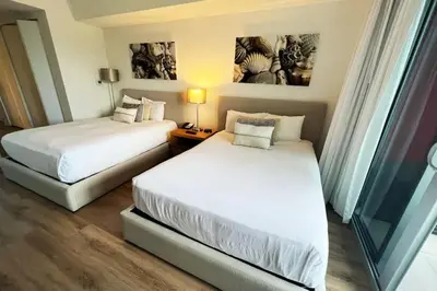 a hotel room with two beds and a window at Sunlit BeachWalk Studio, 2 Full Beds, Coastal Charm in Hallandale Beach