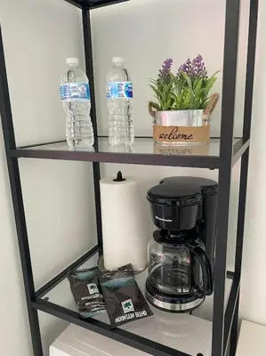 a shelf with a coffee maker and water bottles at Sunlit BeachWalk Studio, 2 Full Beds, Coastal Charm in Hallandale Beach