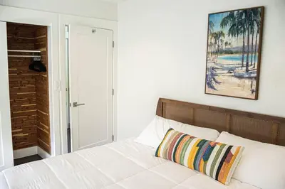 a bedroom with a white bed with a painting on the wall at Villa Palma-Hollywood Beach-Private Pool & Beachwalk! in Hollywood