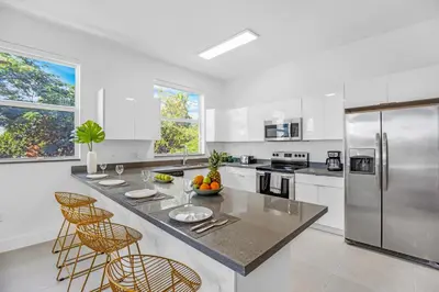 a kitchen with white cabinets and a large island with bar stools at Up to 12 Guests! Modern villa near Wynwood in Miami