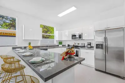 a white kitchen with a stainless steel refrigerator at Up to 16 guests! Modern house near Wynwood in Miami