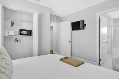 a white bedroom with a bed with a tv on the wall at Sistrunk Shades Villas #1 - Brand New Townhomes Downtown Fort Lauderdale in Fort Lauderdale