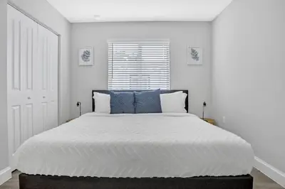 a white bedroom with a large bed with blue pillows at 30 Guests 3 Identical Brand New Townhomes in Downtown Fort Lauderdale in Fort Lauderdale