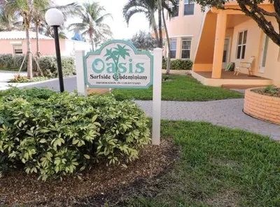a sign in front of a building with a bush at 310 Oasis Paradise in Hollywood