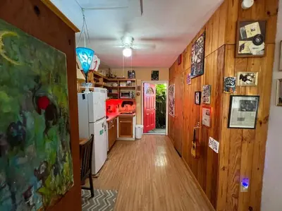 a kitchen with wooden walls and a hallway with a refrigerator at Miami Bungalow Oasis near Everglades & The Keys in Cutler Bay
