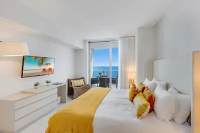 a bedroom with a large bed with a view of the ocean at Insane Ocean View Balcony Beachfront Condo Pool in Hollywood