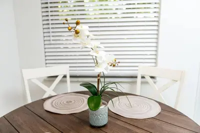 a table with two plates and a vase with white flowers at Heart of Wilton 3 Recently Remodeled in Fort Lauderdale