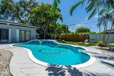 a swimming pool in the backyard of a house at Heated Pool Tropical Backyard 3 Bedrooms, 12 min to the Ocean in North Miami Beach