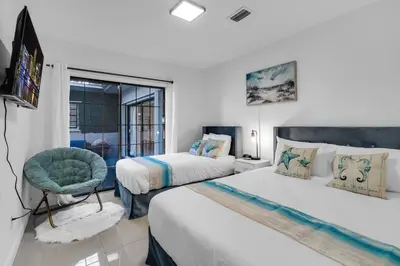 a bedroom with two beds and a chair and a television at Heated Pool Tropical Backyard 3 Bedrooms, 12 min to the Ocean in North Miami Beach