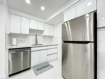 a kitchen with white cabinets and a stainless steel refrigerator at Beach Paradise a cozy ocean view condo on the beach with free parking in Hollywood