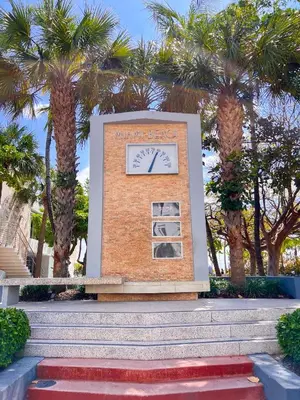 a sign with a clock in front of palm trees at Rooftop-Pool King Bed Suite on Ocean Dr C305 in Miami Beach