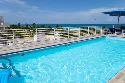 a large swimming pool with the ocean in the background at King bed Rooftop Suite Ocean Dr C304 in Miami Beach
