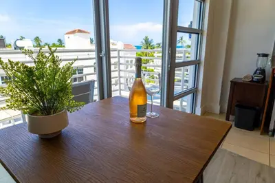 a bottle of wine sitting on a wooden table with a plant at Rooftop-Pool Suite on Ocean Dr C505 in Miami Beach
