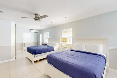 two beds in a white bedroom with blue sheets at Hollywood Bungalow in Hollywood