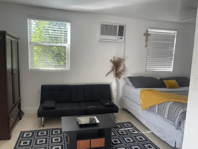 a bedroom with a bed and a couch and windows at Master King Suite by Hard rock stadium and casino in Miami