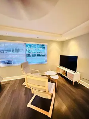a living room with a tv and a chair and a table at Ft Lauderdale - Oasis in Fort Lauderdale