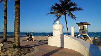 people walking on a beach with palm trees and a lighthouse at Ft Lauderdale - Oasis in Fort Lauderdale
