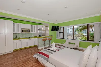 a bedroom with a white bed and green walls at Beach Front Studio Miami Beach in Miami Beach