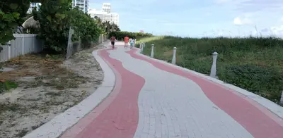 two people walking down a red brick sidewalk at Beach Front Studio Miami Beach in Miami Beach