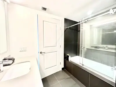 a bathroom with a sink and a glass shower door at Lunabase Tropical Refuge in Miami