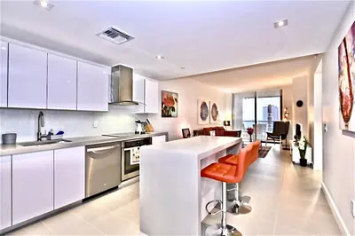 a kitchen with white cabinets and orange chairs in it at Lunabase Tropical Refuge in Miami