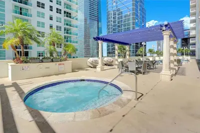 a hot tub in a patio with a blue umbrella at Brickell Bay View Oasis with Pool Hot Tub and Gym in Miami