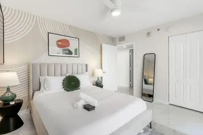 a white bedroom with a large white bed and a mirror at Brickell Bay View Oasis with Pool Hot Tub and Gym in Miami