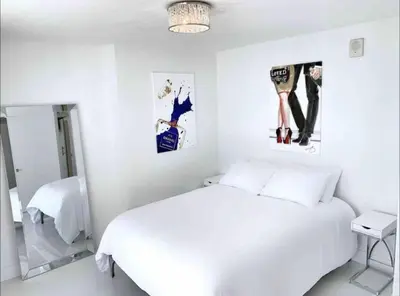 a white bedroom with a bed and two pictures on the wall at Luxury Sky Villa with City and Ocean Views in Miami