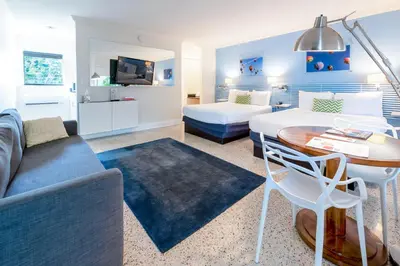 a living room with a couch and a bed and a table at Victoria Park Hotel in Fort Lauderdale