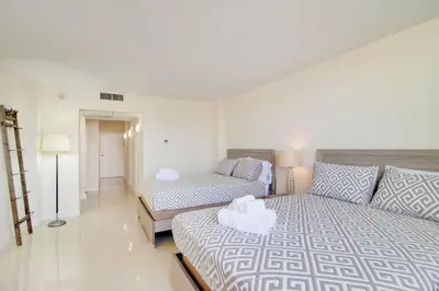 a bedroom with two beds and a couch at Family Beach Home w Ocean & Bay Views - Upgraded Corner Unit in Miami Beach