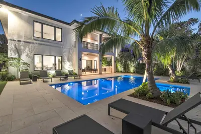 a swimming pool in the backyard of a house with a palm tree at Villa in Coral Gables with Pool Jacuzzi Game Room in Miami